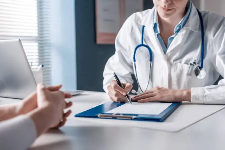 A physician taking notes with a patient across a desk