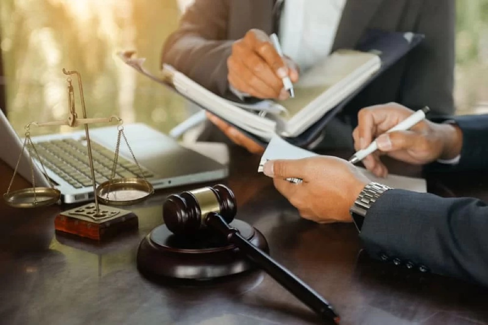 Two attorneys reviewing a case with scales of justice and a gavel on the desk