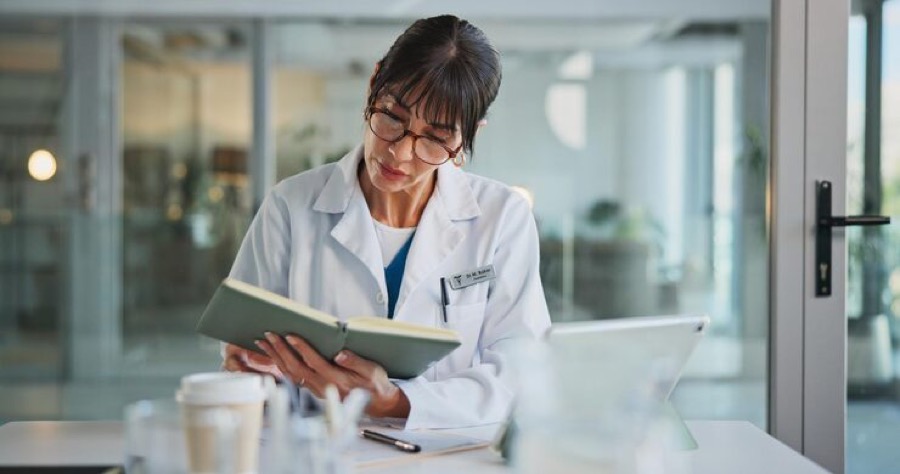 A physician reviewing a case journal at her desk